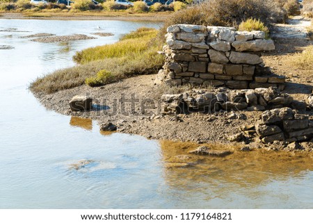 lagoon of ria formosa at low tide with the pillar ruins of an old pedestrian bridge leading to the beach Do Barril where is the cemetery anchors of former tuna fishermen.