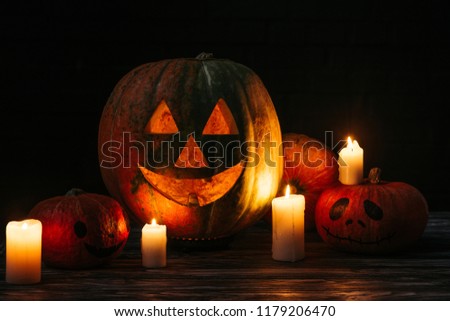 spooky halloween carved pumpkins with candles on wooden table on black background