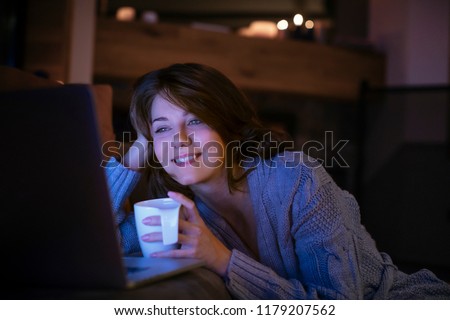 Pretty smiling woman watching a movie on her laptop at home. Royalty-Free Stock Photo #1179207562