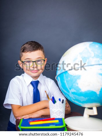 A neat schoolboy sitting at a parton on a black background