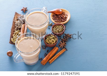 Hot Indian milk tea with spices - cinnamon, cardamom, ginger, cloves, tubby, sweet pepper on a wine background. Copy space