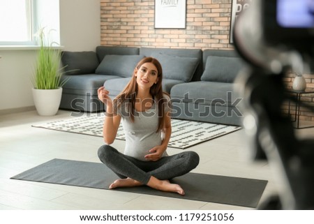 Young pregnant blogger recording video at home