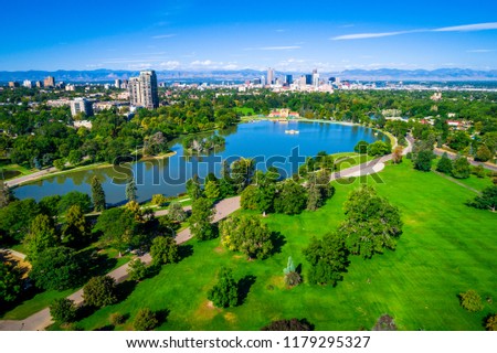 A gorgeous day in the park. City Park aerial drone view with Denver Colorado skyline background green space view high above the mile high city along the Rocky Mountain front range blue pond