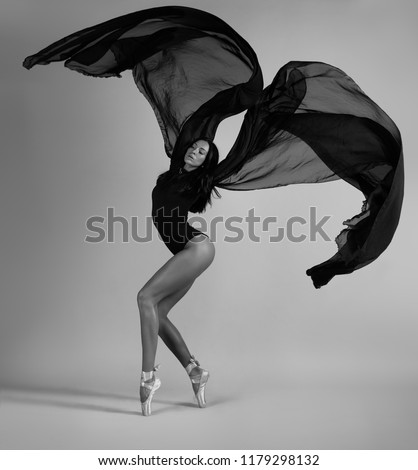 A ballerina posing with a black cloth like a bird. Black and white photo.