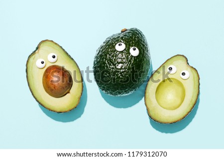 Funny faces avocados on a pastel blue background, creative healthy food concept, top view with clipping path