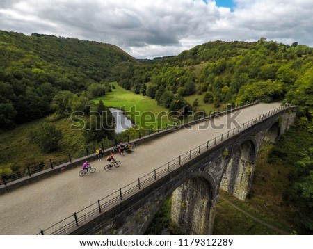 Stunning aerial view of people riding, cycling across a bridge, viaduct in the Peak District National park in England, Bakewell, UK