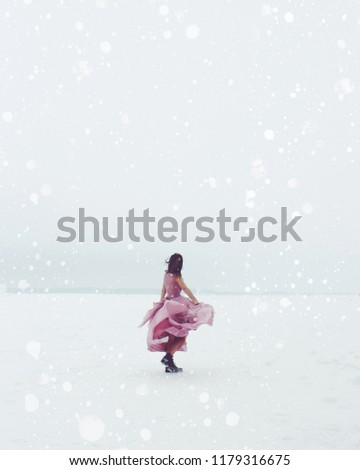 Beautiful girl whirls in winter/
Beautiful happy young woman in pink summer satin dress whirls at the winter background. Her long hair covers her face. Retro styled photo.