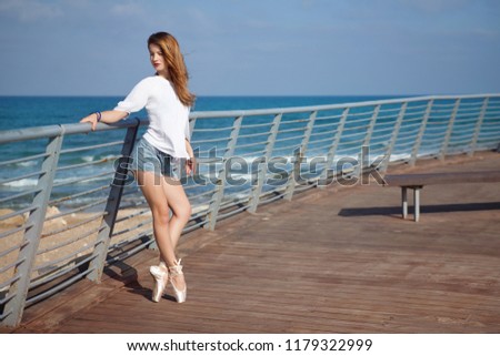Young attractive ballerina training on sea coast wearing casual. Fine art ballet concept. Surreal dancing. Slim girl dance on the ocean beach. Active and healthy women