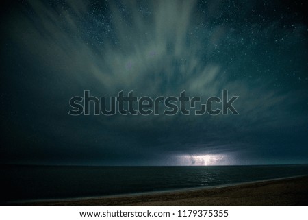 Starry night with thunderstorm and lightning over the sea