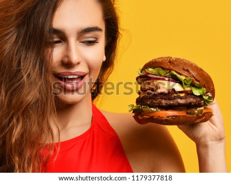 Closeup woman look at big barbecue burger sandwich with hungry mouth happy smiling on yellow background. Fast food concept. 