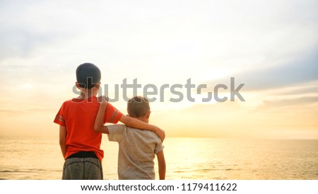 Two brothers enjoying sunset view at the seaside. Additional grains effect to create mood. Royalty-Free Stock Photo #1179411622