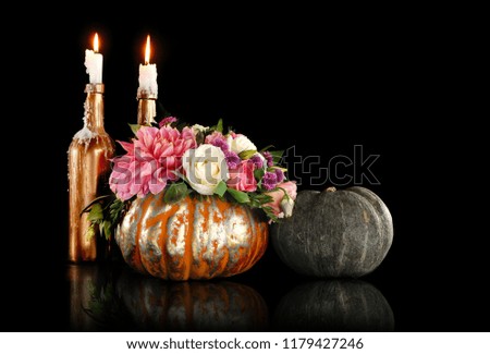 Decorated pumpkin and  burning candles against black background