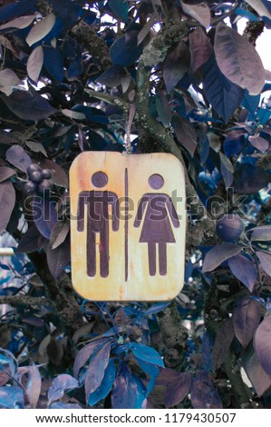 Vertical simple, wooden sign of a gender distinction restroom board