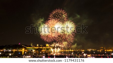 Light green and red fireworks in front of Quebec City during a summer festival.