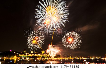 White and orange fireworks in front of Quebec City during a summer festival.
