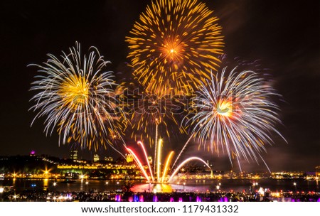 White, orange, and gold fireworks over the Saint-Lawrence River near Quebec City during a Canadian summer festival.