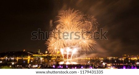 Golden fireworks in a dark sky over the water of a big river in Quebec, Canada.