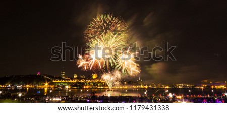 Gold, green, and red fireworks over the Saint-Lawrence River near Quebec City during a Canadian summer festival.