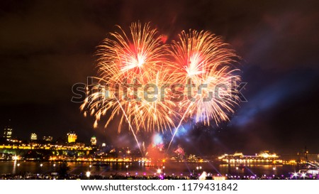 Orange and golden fireworks in front of Quebec City during a summer festival.