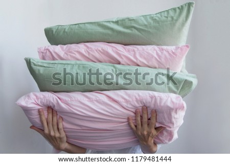 Women's hands hold many multi-colored pillows On a white background