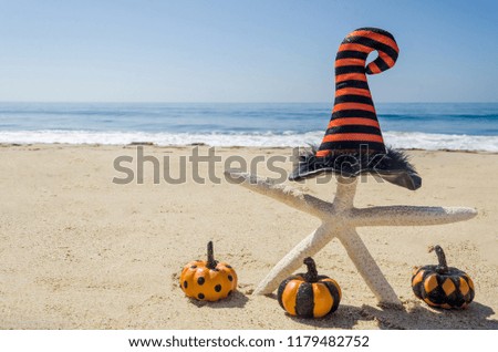 Halloween background with starfishes in the witch's hats on the sandy beach near the ocean 