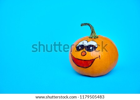 Funny Halloween concept. Cheerful pumpkin with smile face on a blue background