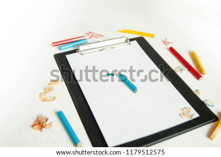 black tablet with blank pages, pencils on white background, creative writing concept. Minimalist working writer. High key still Life with copy space.