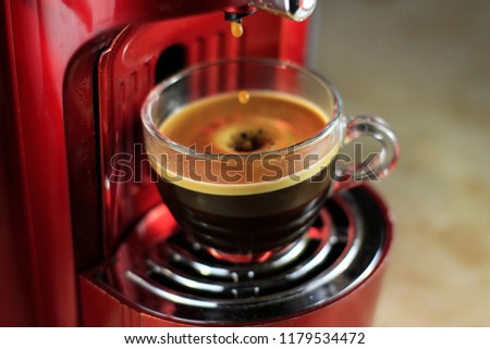 Portrait of a cup of coffee on a coffee machine while the coffee is dropping down