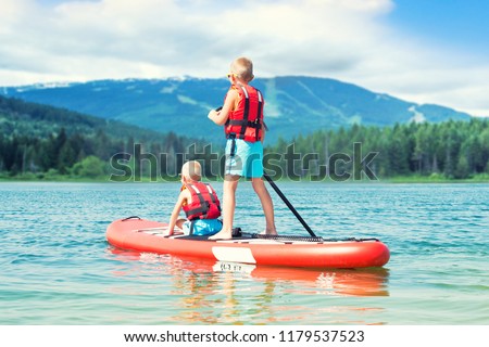 Two brothers swimming on stand up paddle board.Water sports , active lifestyle.