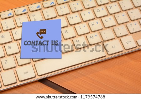 Contact us wrriten on notepad with computer keyboard in background