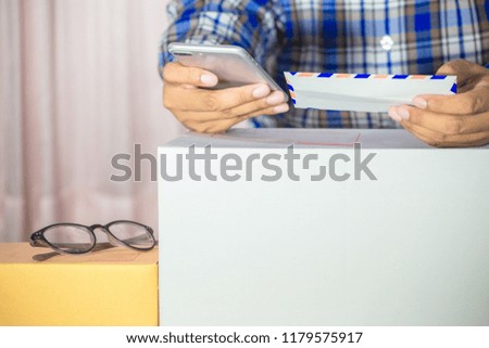 Businessman working with mobile phone and packing brown parcels box at home office. hands seller prepare product ready for deliver to customer. Online selling, e-commerce Start up shipping concept.