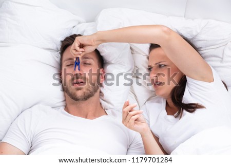 Frustrated Young Woman Trying To Stop Man's Snoring With Clothespin On Bed Royalty-Free Stock Photo #1179701284