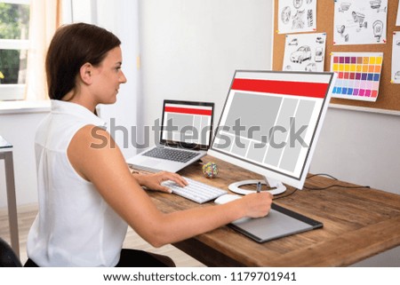 Female Designer Using Computer Over Wooden Desk
