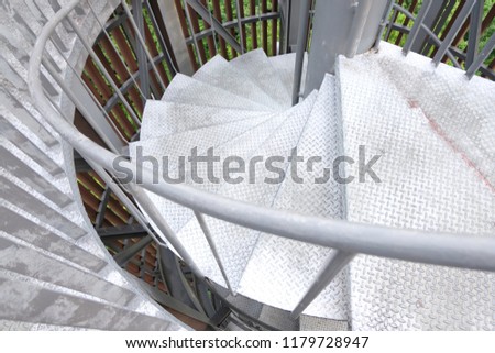 A steel spiral staircase with tree background