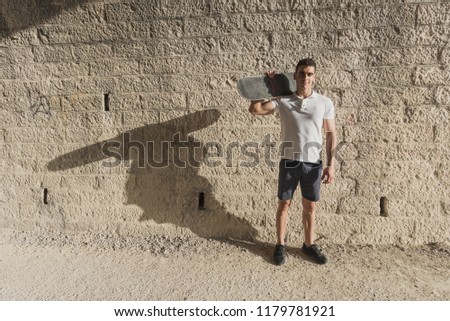 Young man in tunnel with skateboard posing