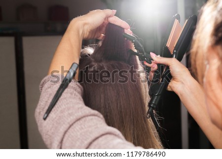 professional hairdresser clipping hair of a young model with a hairpin before making a corrugating coiffure in a beauty salon Royalty-Free Stock Photo #1179786490