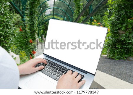 Laptop laying on woman knees in green park in summer mockup