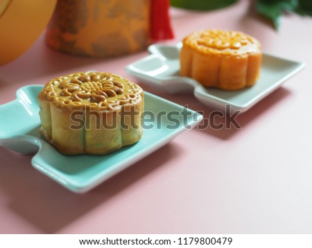 Chinese Mid-Autumn Festival celebration with traditional mooncakes on jigsaw puzzle pattern plate over pastel pink background. Holidays food and dessert concept. (selective focus, space for text)