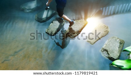 Man across stepping stones to cross a stream. Royalty-Free Stock Photo #1179819421