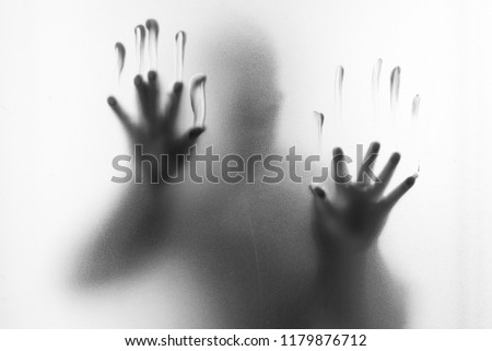 Shadow blur of horror man.Hands on the glass.Dangerous man behind the frosted glass.Mystery man.Halloween background.Black and white picture.Blur picture