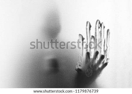 Shadow of horror man wearing a gas mask.Dangerous man behind the frosted glass.Mystery man.Halloween background.Black and white picture.Blur picture