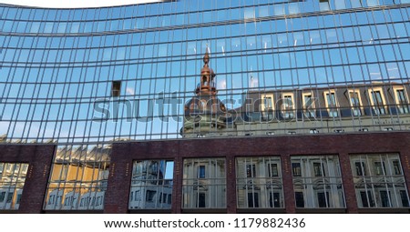 Clear reflections of ancient building in glass wall of modern building. Bright blue sky reflected in rows of full glass windows with open ones. Urban cityscape of Hamburg Germany. Abstract background.