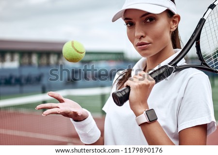 Portrait of forceful woman playing tennis in indoor court, focus on tennis racket hitting ball, copy space