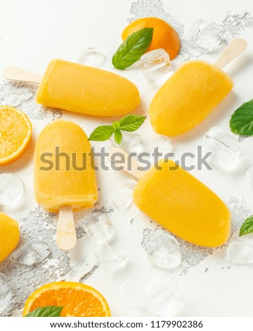 Popsicles, ice lollies on stick with sweet orange juice on white background with ice