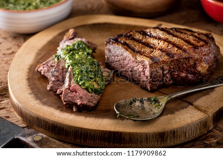 A delicious medium rare fire grilled argentina style steak with chimichurri verde sauce. Royalty-Free Stock Photo #1179909862
