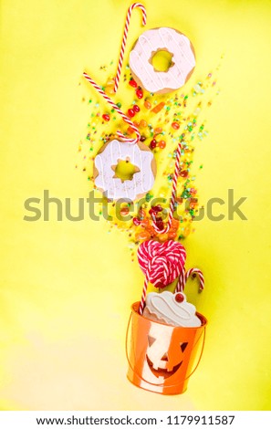 Halloween sweets concept, bucket in the form of a festive pumpkin, full of sweets and candies, cookies, jellies, desserts, bright yellow background top view copy space