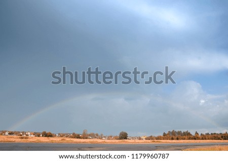 A colorful rainbow in the sky above a village, road