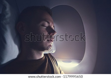 Traveling by airplane. Young passenger sleeping during flight. Royalty-Free Stock Photo #1179995650