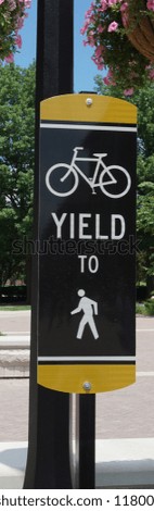 Cars yield to bike but those bikers here must yield to pedestrians.  Order and rules for safe transportation of all sorts.  Outdoor healthy travel with signs for logistics                             