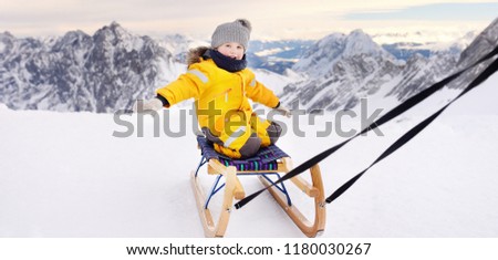 Cute caucasian little boy sledding in Alps mountains. Winter fun for family with kids